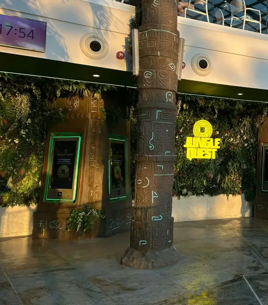 Rzeźbiona kolumna i zielona ściana stanowisk Jungle Quest w Suntago