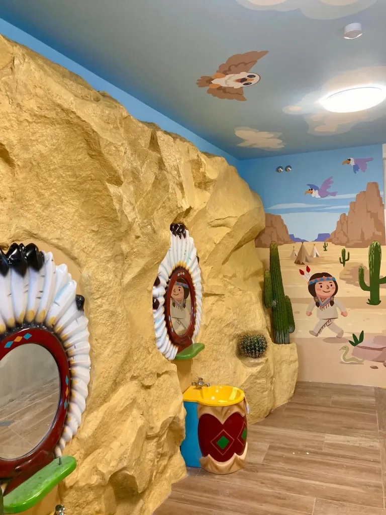 Skalna ściana z umywalkami i mural oglądane z przeciwnej strony wnętrza